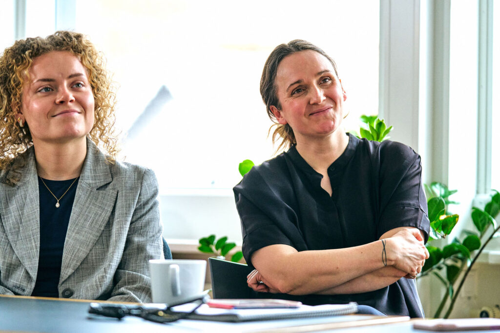 To medarbejdere fra CFSA lytter smilende på et møde