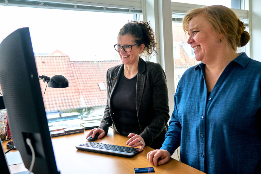 To medarbejdere hos CFSA kigger på en skærm ved et hæve-sænkebord